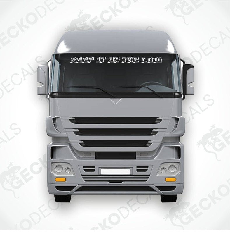 A decal with the text 'KEEP IT ON THE LOW' positioned on the windscreen of a gray truck.