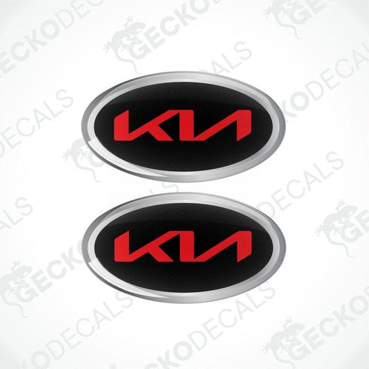 Two oval-shaped vinyl decals with 'KIA' written in bold letters, predominantly red with black and silver accents.
