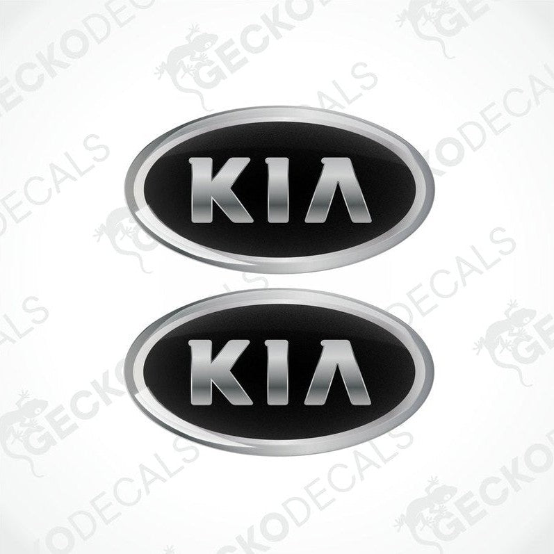Two domed vinyl stickers with a KIA logo, one black and one silver, both with a polyurethane coating.