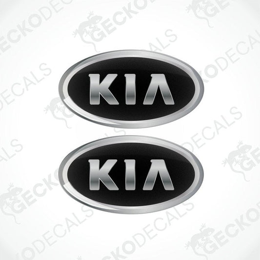 Two domed vinyl stickers with a KIA logo, one black and one silver, both with a polyurethane coating.