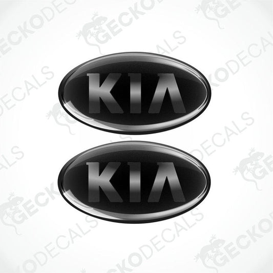 Two black oval-shaped vinyl decals with the KIA brand logo in white text.