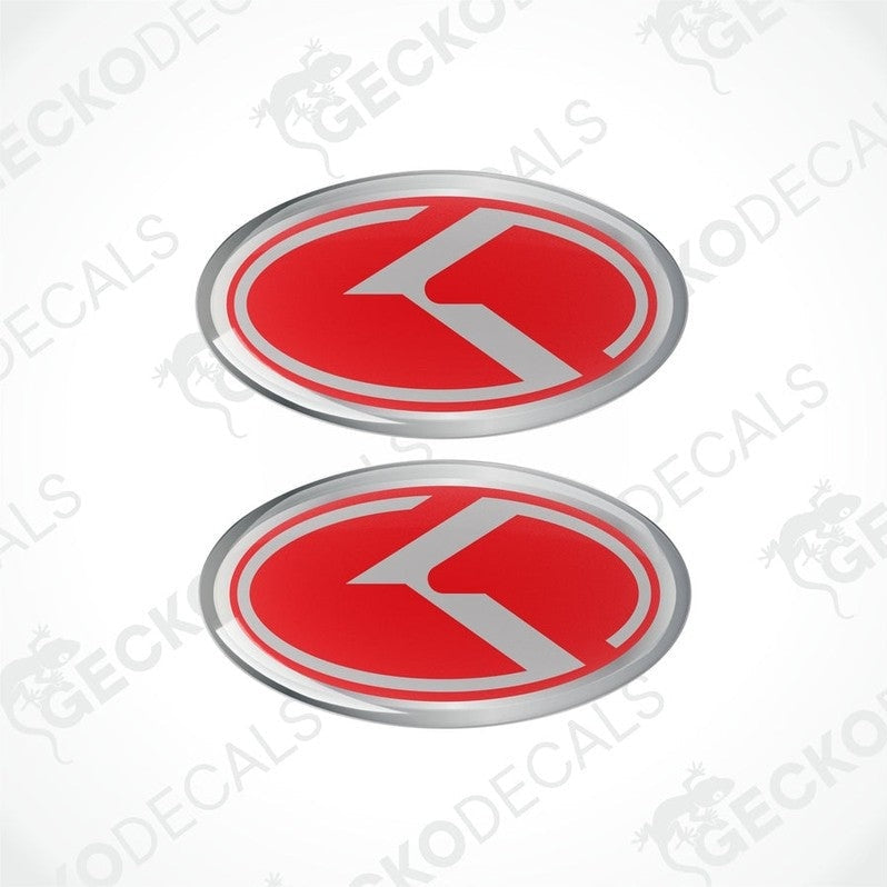 Two oval vinyl stickers with a red and grey design and the letter 'KIA' in the center, placed on a white background.