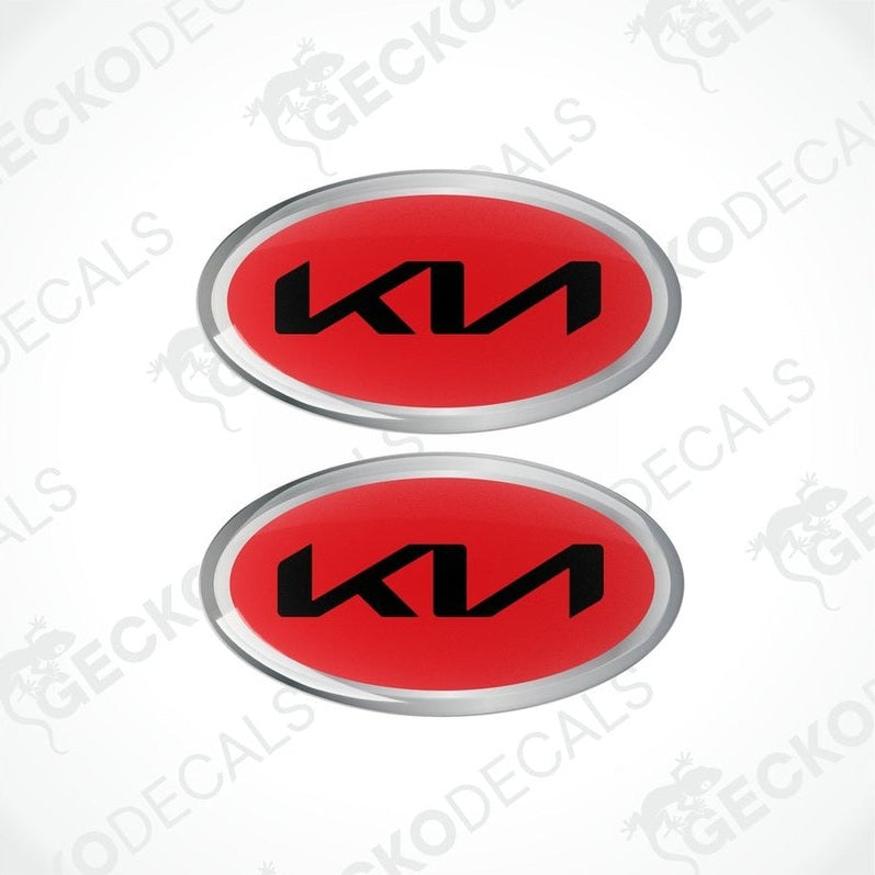 Two oval-shaped vinyl decals with 'KIA' written in bold letters, predominantly red with black and silver accents.