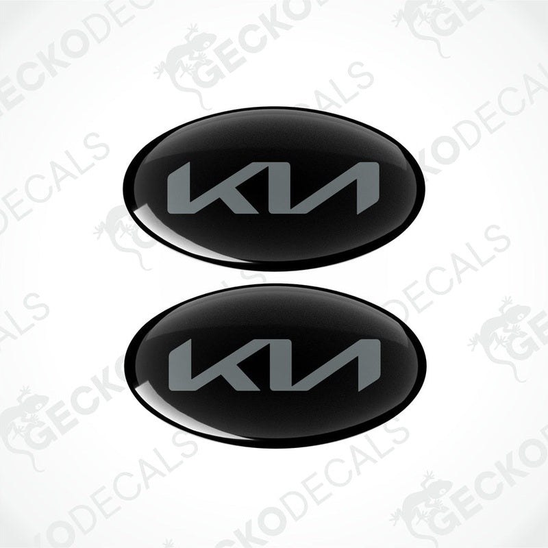 Two black oval-shaped vinyl decals with the KIA logo in grey.