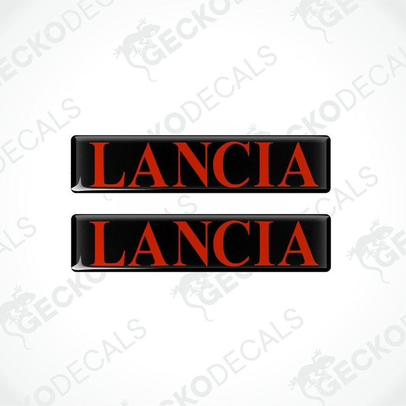 Two rectangular black vinyl decals with the word 'LANCIA' written in red letters.