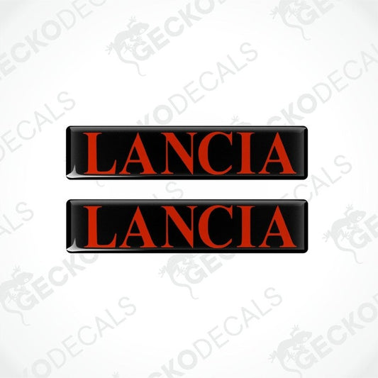 Two rectangular black vinyl decals with the word 'LANCIA' written in red letters.