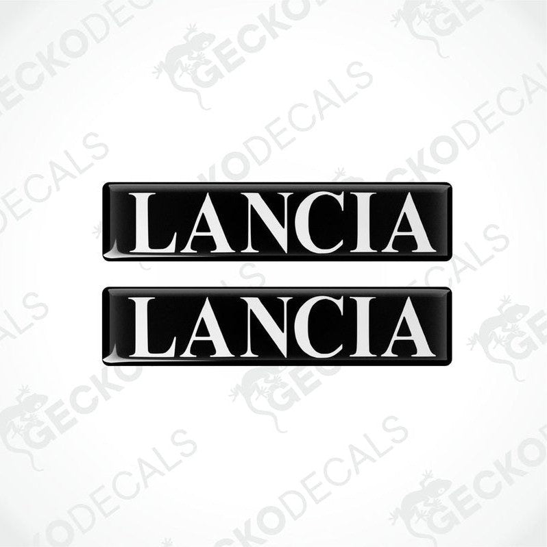 Two rectangular black vinyl decals with the word 'LANCIA' written in white letters.