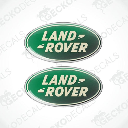 Two green, silver, and white oval-shaped vinyl decals with the text 'LAND ROVER' on them.