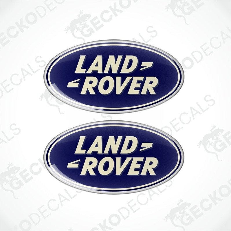 Two blue, silver, and white oval-shaped vinyl decals with the text 'LAND ROVER' on them.