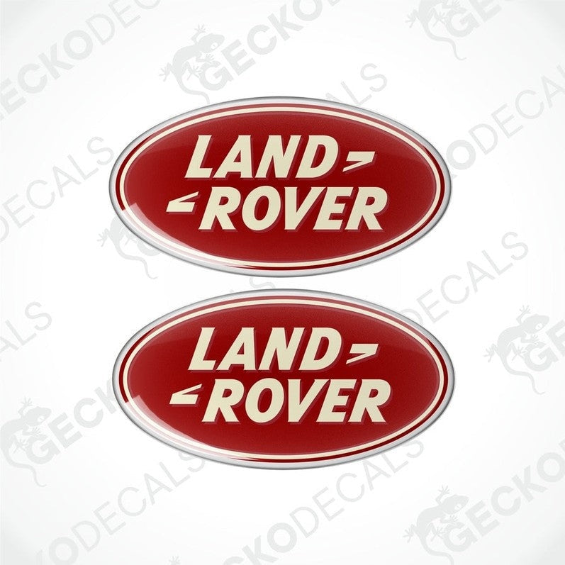 Two red, silver, and white oval-shaped vinyl decals with the text 'LAND ROVER' on them.