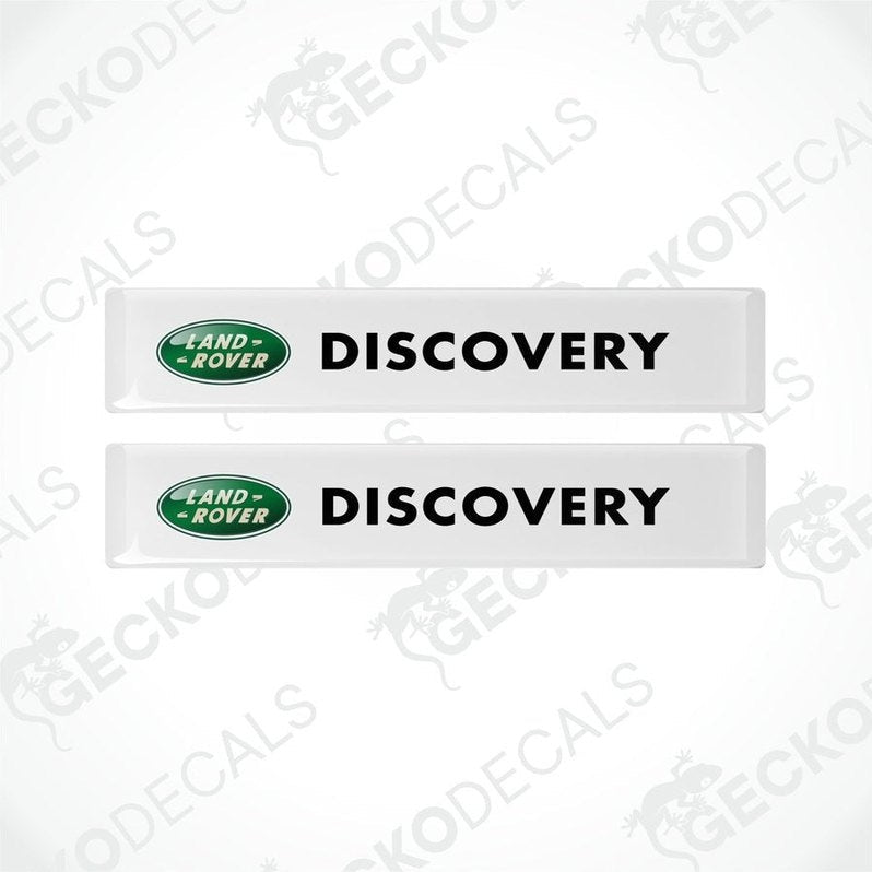 Two white vinyl decals with the text 'DISCOVERY' and the Land Rover logo in green and black.