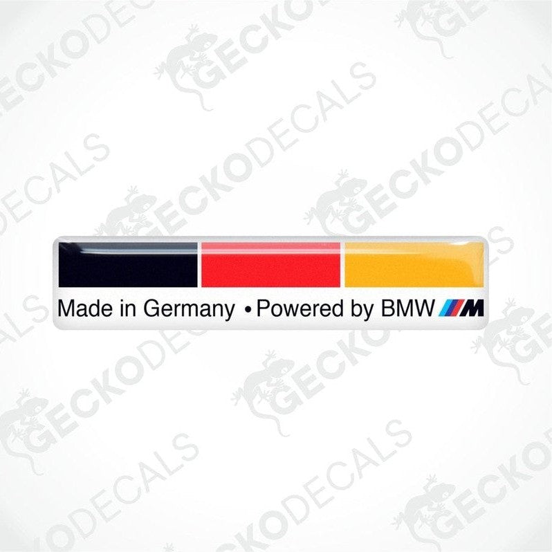 Vinyl stickers with the words "MADE IN GERMANY POWERED BY BMW", on a white background and in the colors of the German flag.