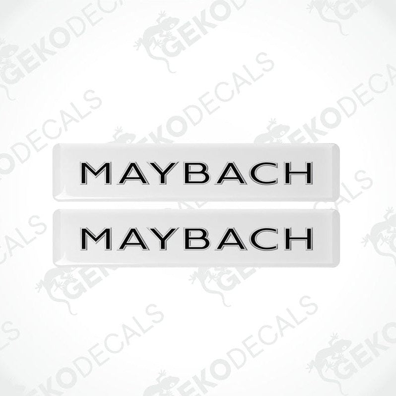 Two rectangular white vehicle decals with the text 'MAYBACH' in capital letters