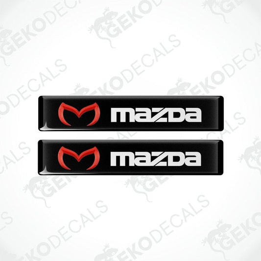 Two black vinyl stickers with a red and white Mazda logo on them.
