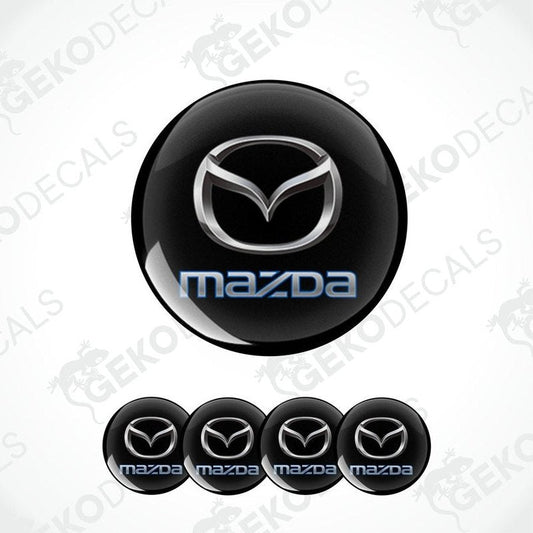 A set of black round car decals with the Mazda logo in the center and smaller copies of the logo on the sides.
