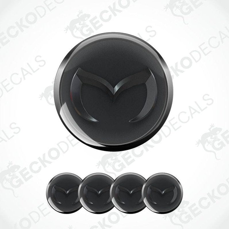 Black car emblem with a silver border on a white background, featuring the Mazda logo.