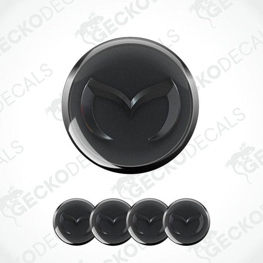 Black car emblem with a silver border on a white background, featuring the Mazda logo.