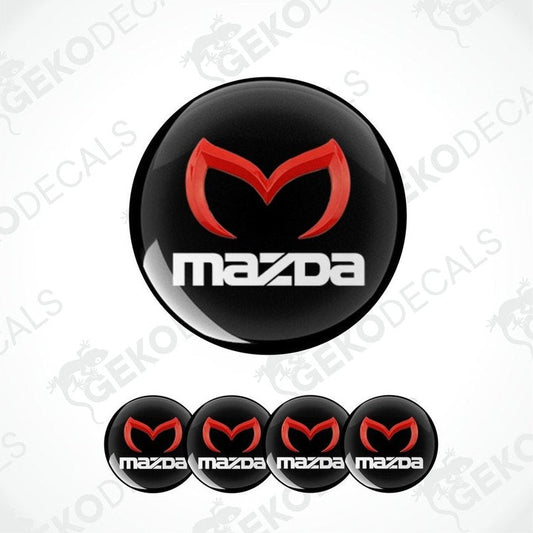 A set of four black vinyl stickers with a red and white MAZDA logo, designed for use on car wheels.