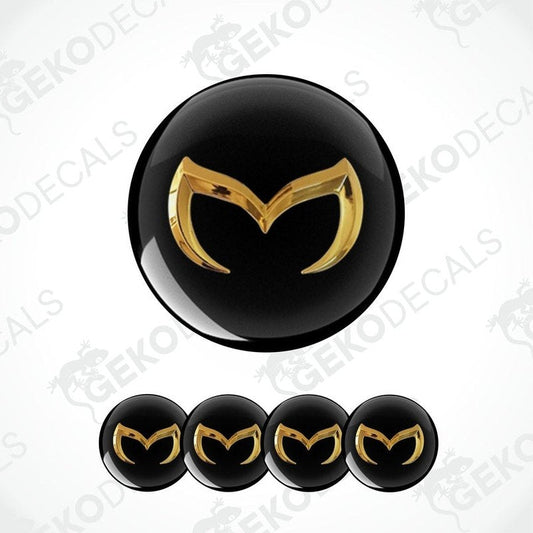 Set of four black and gold Mazda car wheel decals and one emblem decal.