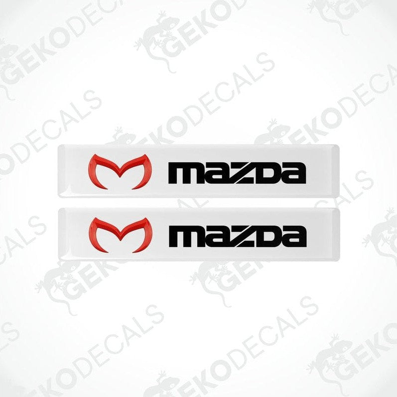 Two white vinyl stickers with a red and black Mazda logo on them.