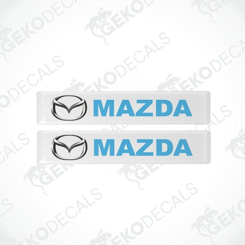 Two white, blue, and silver Mazda branded vinyl decals.