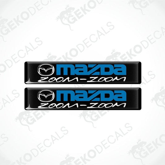 Two black vinyl stickers with the text 'MAZDA ZOOM-ZOOM' in blue.