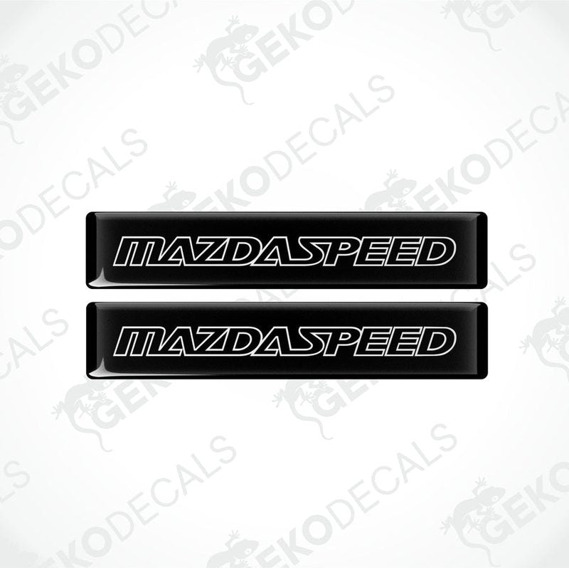 Two black rectangular car decals with 'MAZDASPEED' written in white letters.