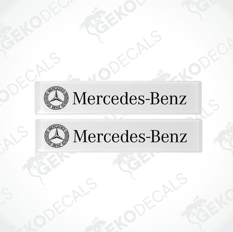 Two white vinyl stickers with the Mercedes-Benz logo printed on them.