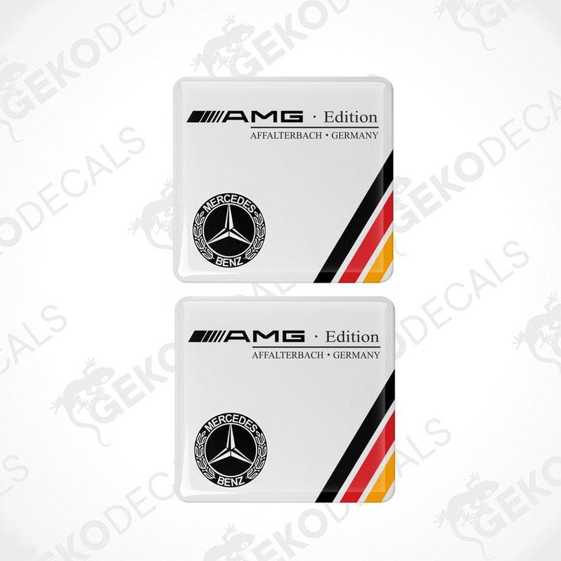 Two white Mercedes-Benz AMG Edition car decals with red and yellow stripes and the Mercedes-Benz logo.