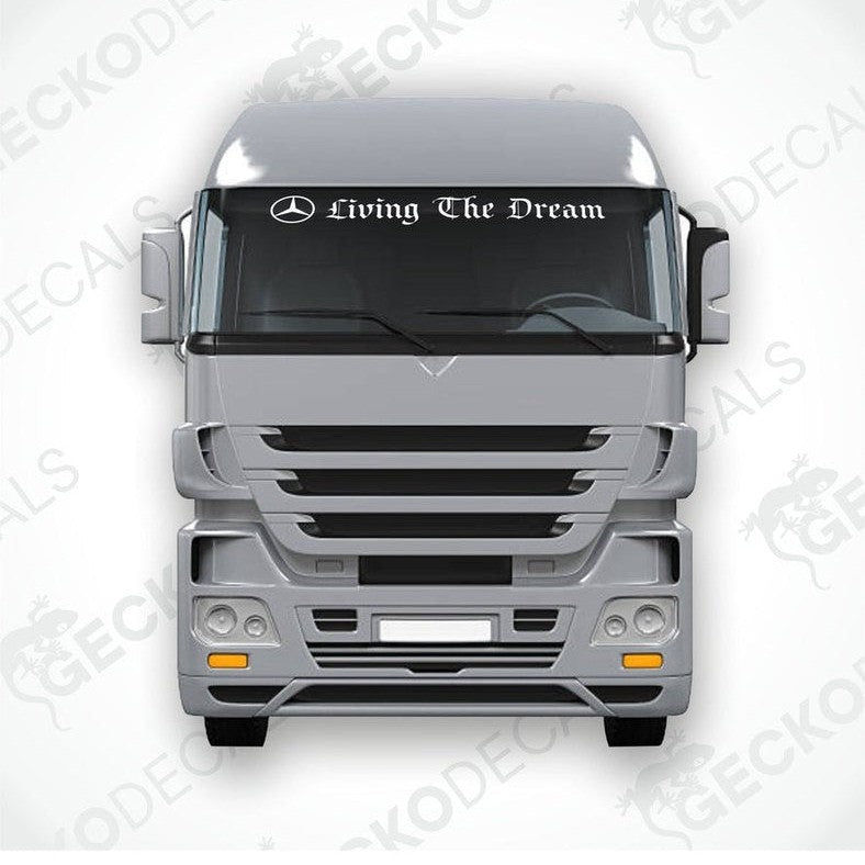 A sticker with the text 'Living The Dream' placed on the windscreen of a gray Mercedes-Benz truck.