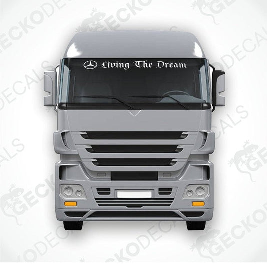 A sticker with the text 'Living The Dream' placed on the windscreen of a gray Mercedes-Benz truck.