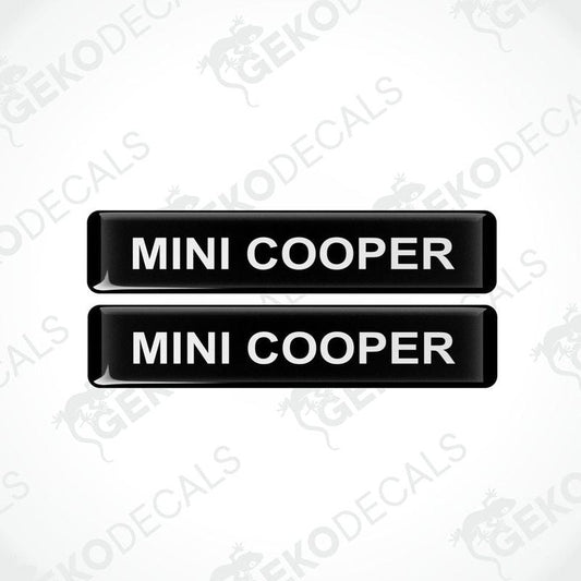 Two black rectangular car decals with the text 'MINI COOPER' in white.
