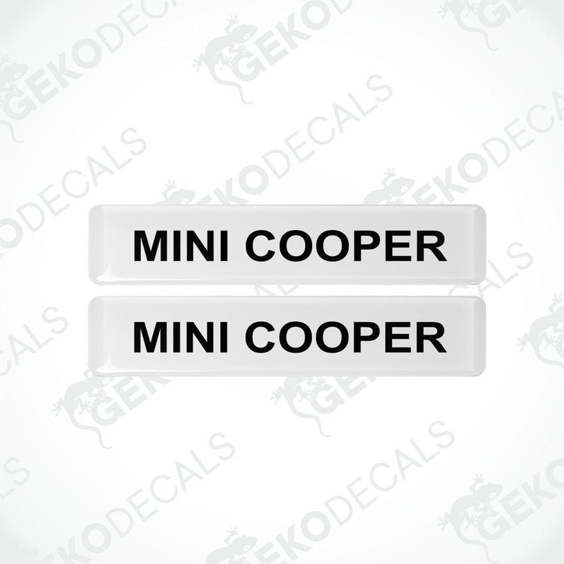 Two white rectangular car decals with the text 'MINI COOPER' in black.