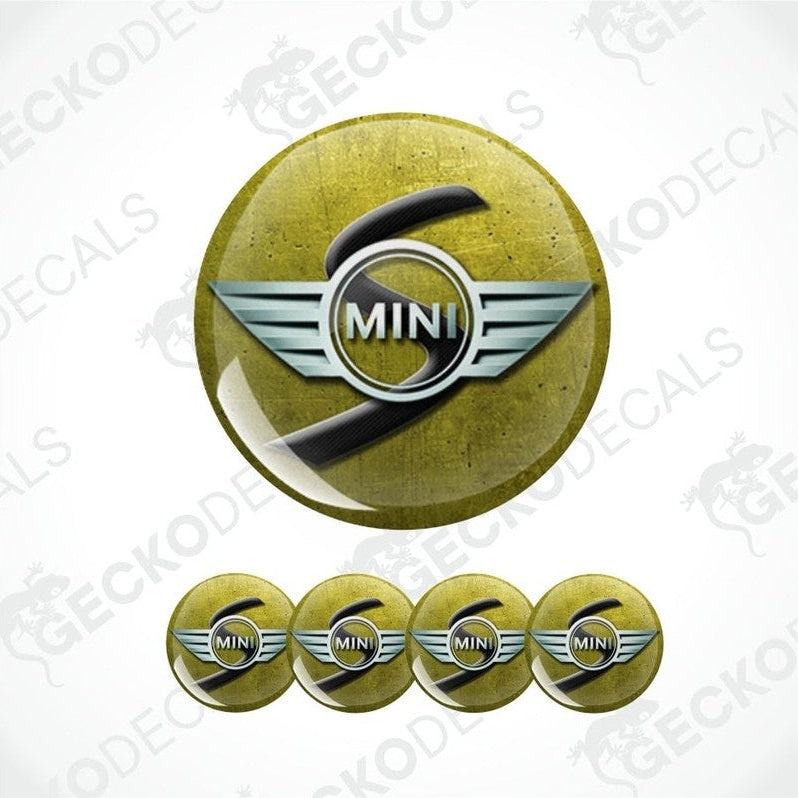 a three-dimensional gray Mini and black S logo on a mustard yellow scratched metal background 