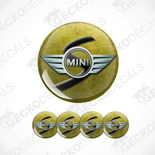 a three-dimensional gray Mini and black S logo on a mustard yellow scratched metal background 
