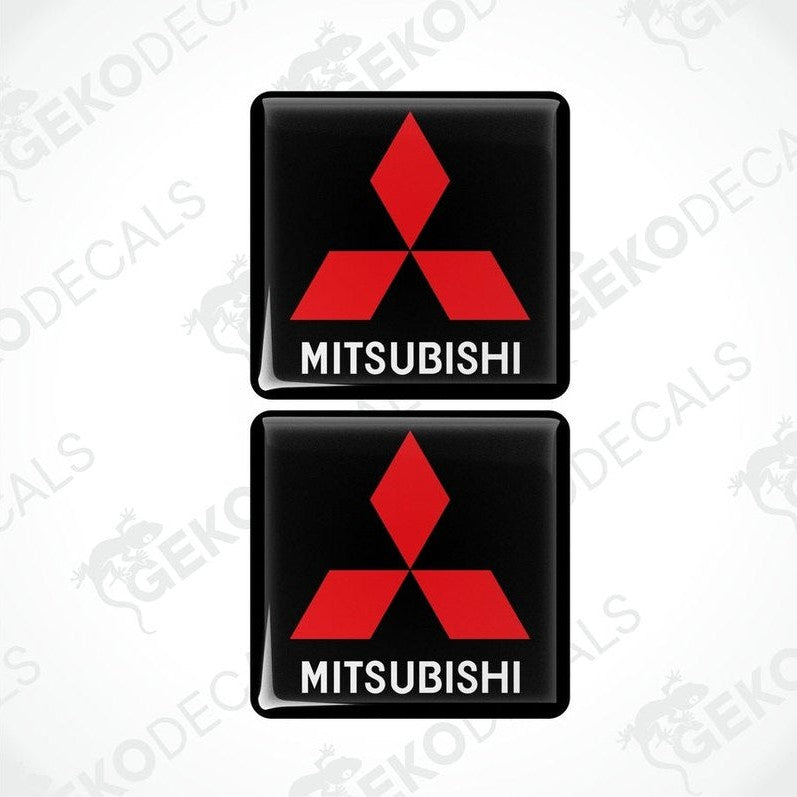 Two black vinyl stickers with a red Mitsubishi logo on each, placed against a white background with the text 'MITSUBISHI' below each sticker.