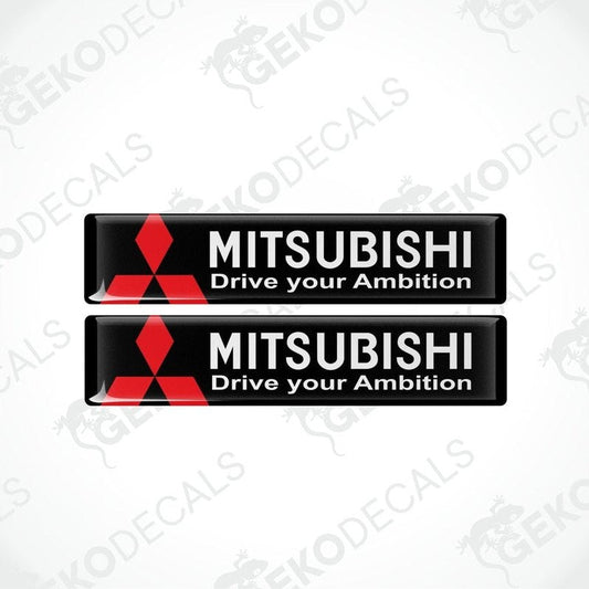 Two rectangular black vinyl decals with the Mitsubishi logo and the text 'MITSUBISHI Drive your Ambition' in white and red.