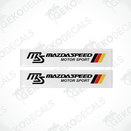 Two white vinyl stickers with red, black, and yellow MazdaSpeed Motor Sport logo, placed on a white background.