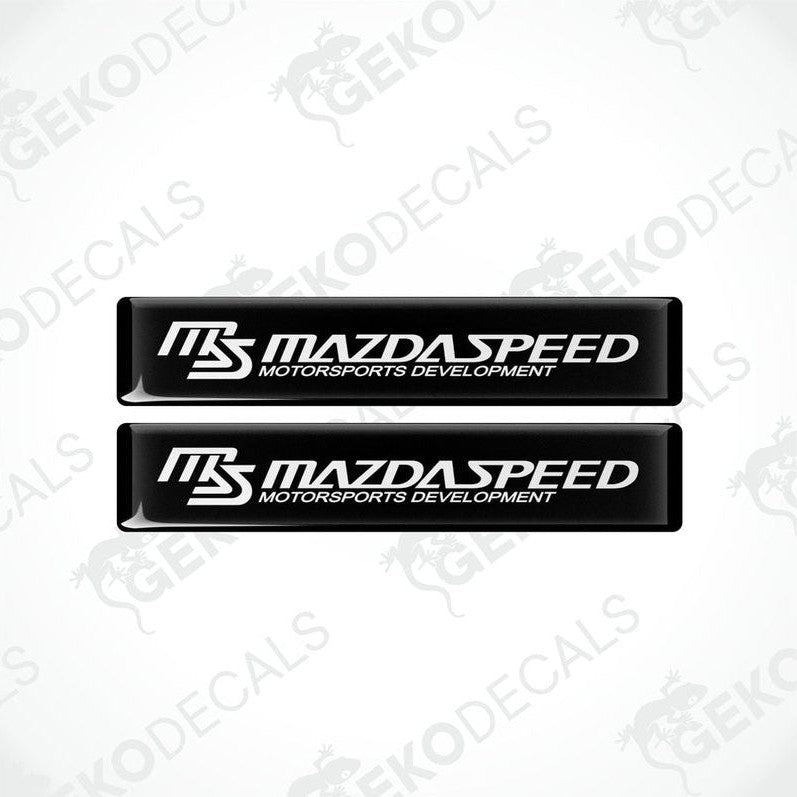 Two black and white rectangular decals with 'MAZDASPEED MOTORSPORTS DEVELOPMENT' text.