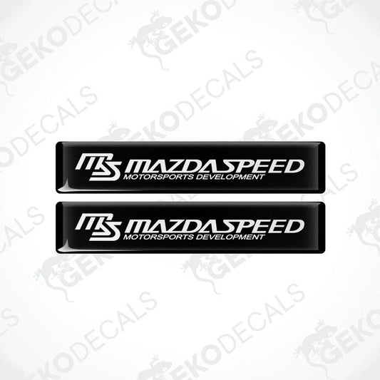 Two black and white rectangular decals with 'MAZDASPEED MOTORSPORTS DEVELOPMENT' text.