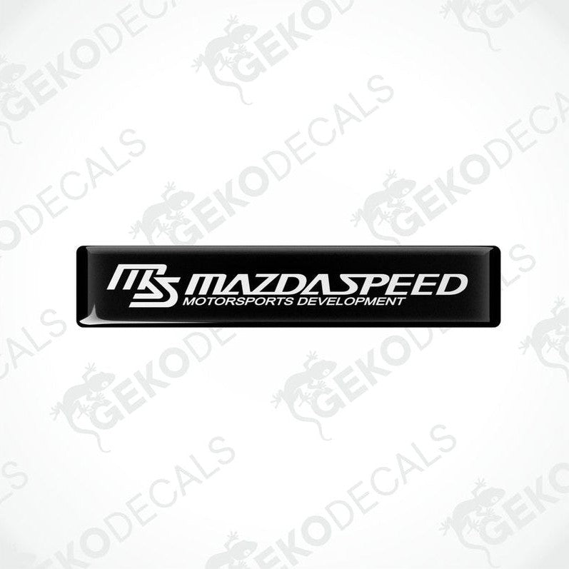 Black and white rectangular decals with 'MAZDASPEED MOTORSPORTS DEVELOPMENT' text.