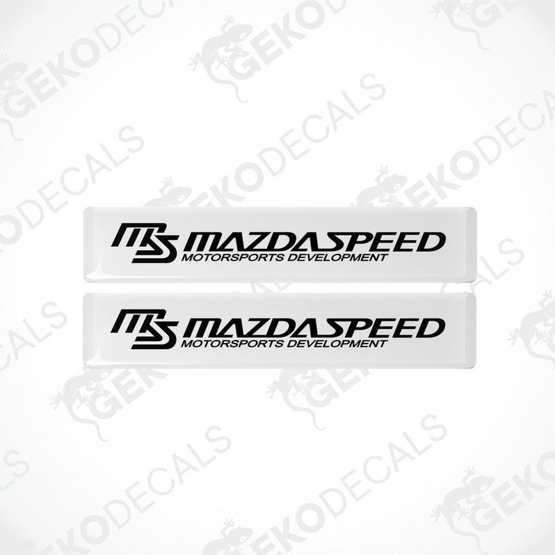 Two white and black rectangular decals with 'MAZDASPEED MOTORSPORTS DEVELOPMENT' text.