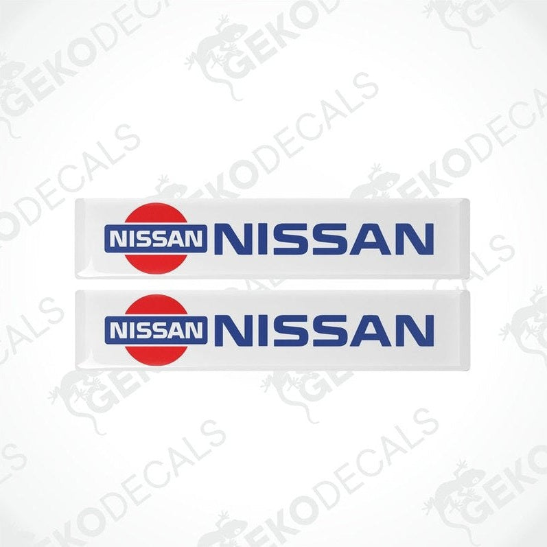 Two vinyl decals with polyurethane coating featuring the NISSAN logo, predominantly red and white in color.