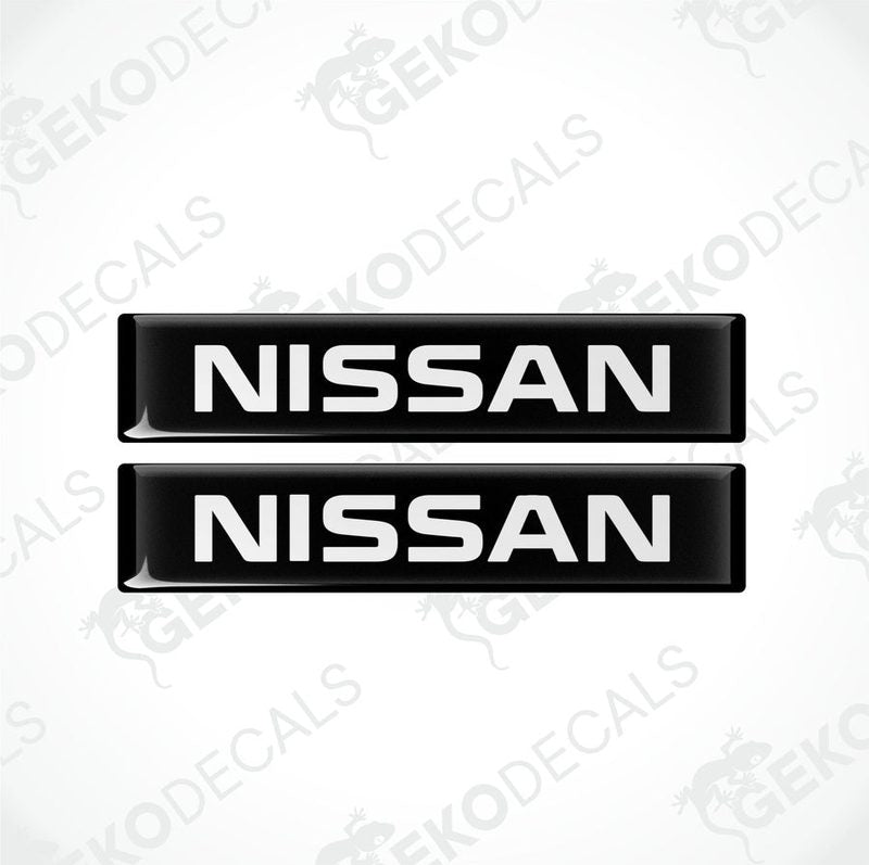 Two black rectangular car decals with the text 'NISSAN' in white uppercase letters