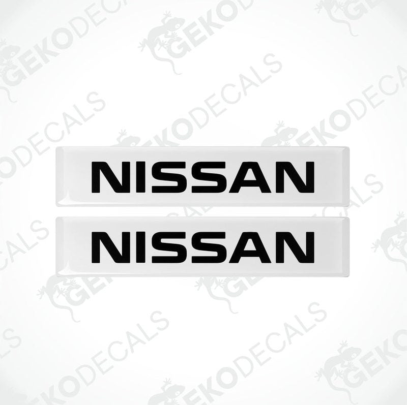 Two withe rectangular car decals with the text 'NISSAN' in white uppercase letters