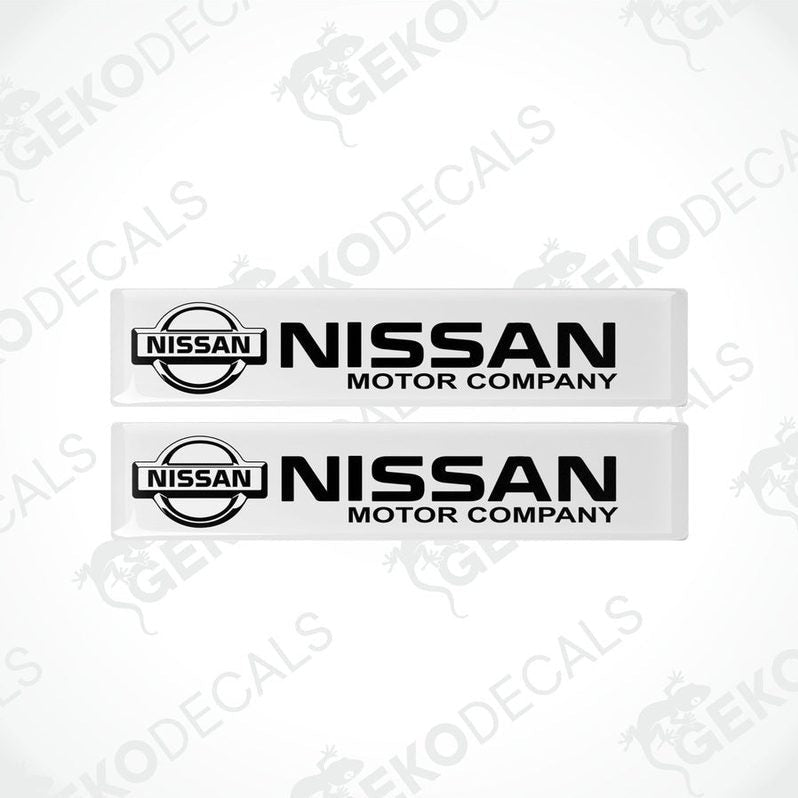 Two white vinyl stickers with the NISSAN Motor Company logo in black.