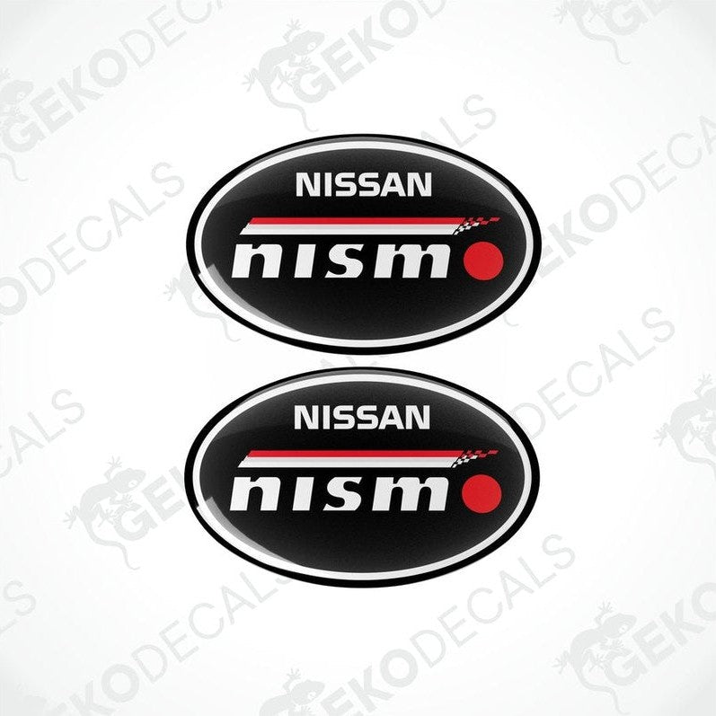 Two oval-shaped vinyl decals with the NISSAN NISMO logo in black, red, and white colors.