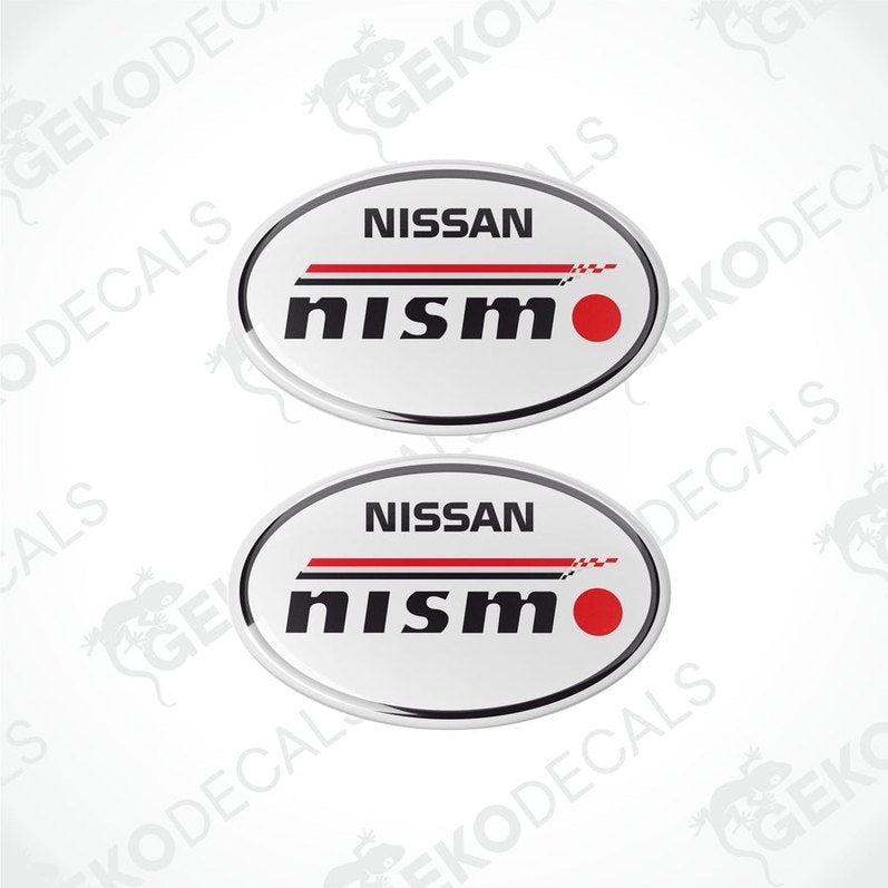 Two oval-shaped vinyl decals with the NISSAN NISMO logo in white, red, and black colors.