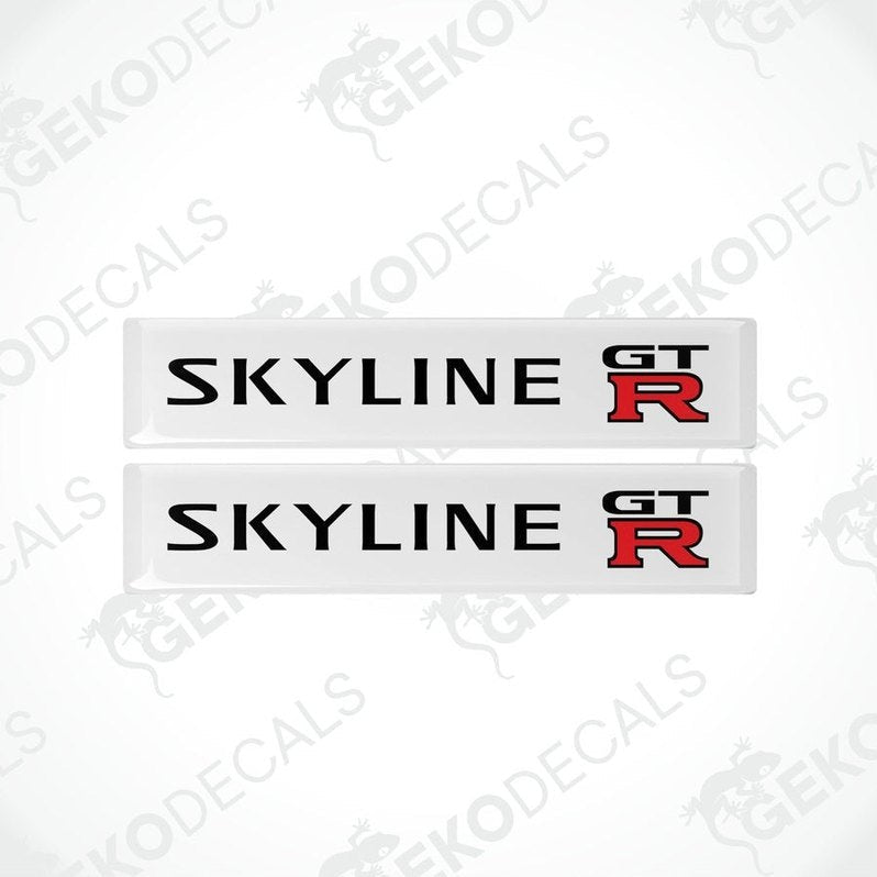 Two white, red, and black decals with the text 'SKYLINE GT R' on them, designed for vehicle use.