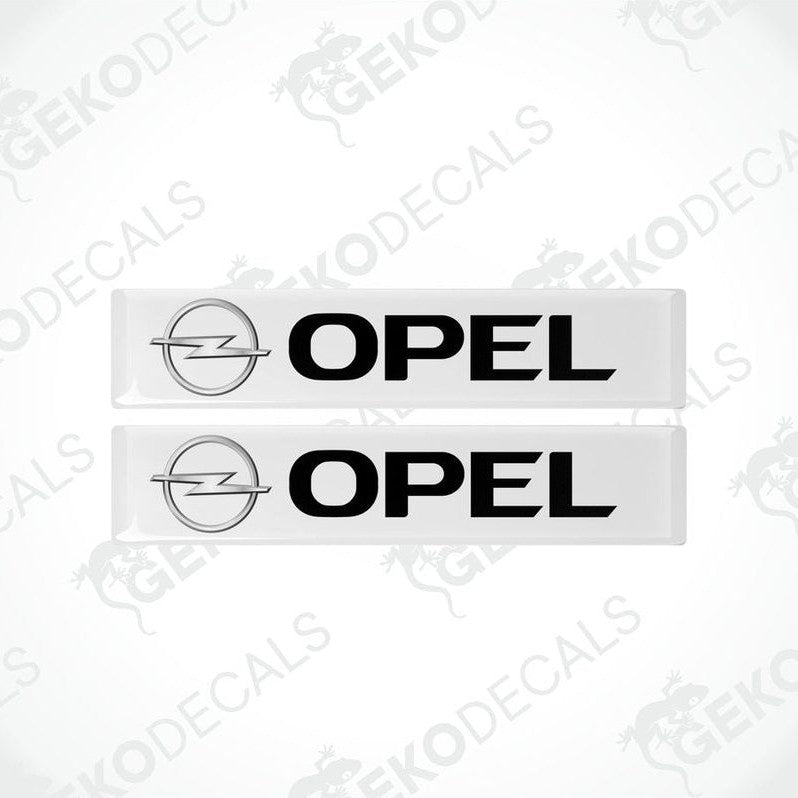 Two withe vinyl stickers with the word 'OPEL' and the logo of the Opel brand on a black background.